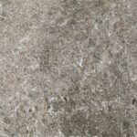 Close-up of a textured gray stone surface featuring intricate patterns and a blend of lighter and darker shades, creating a natural, earthy appearance characteristic of Travertine - Cappuccino.