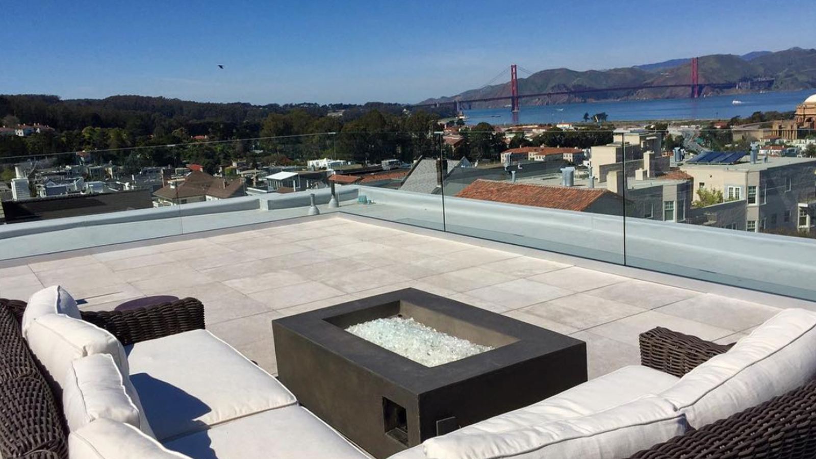 residential roof deck overlooking golden gate bridge with fireplace and cream stone look porcelain pavers. 