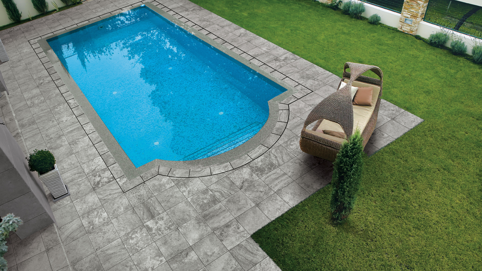 porcelain travertine pavers around a blue pool in a backyard. 