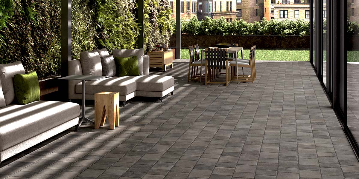 A spacious patio area paved with cobblestone-effect porcelain tiles offered by Archatrak.