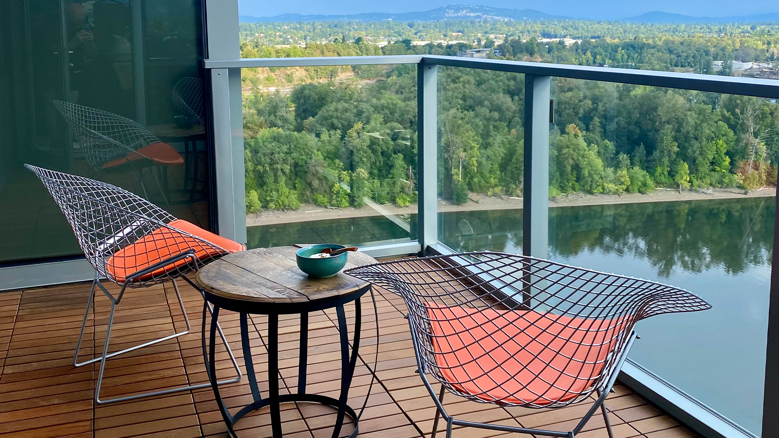 small interlocking ipe tile balcony with chairs, small table and class railing. 