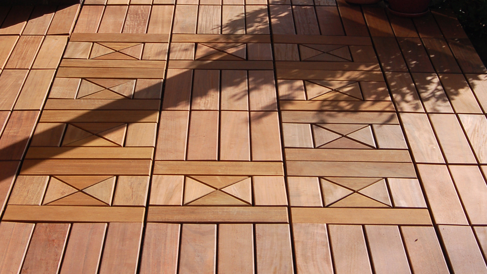 close of view of interlocking ipe tiles on a balcony or patio, showing two different tile patterns. 