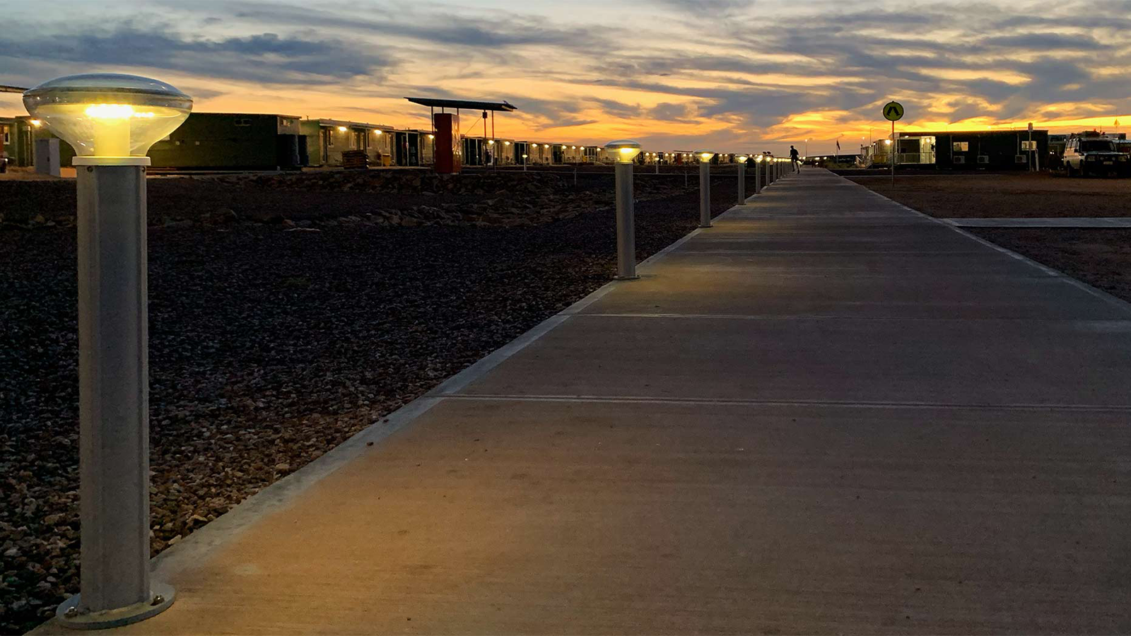 multiple solar bollard lights on the left side of a pedestrian walking path. 