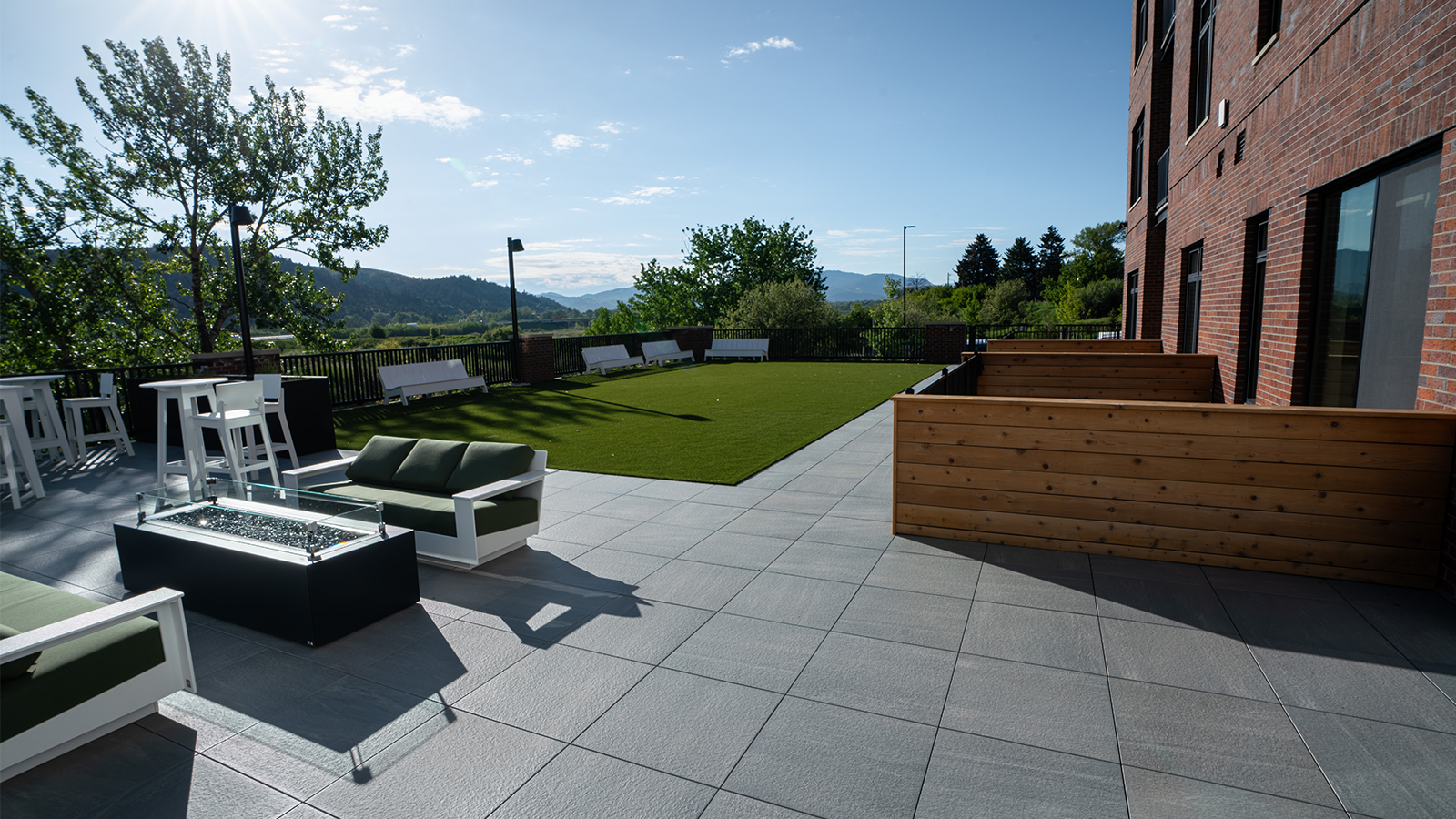 grey porcelain patio pavers with green patio couches and firepit