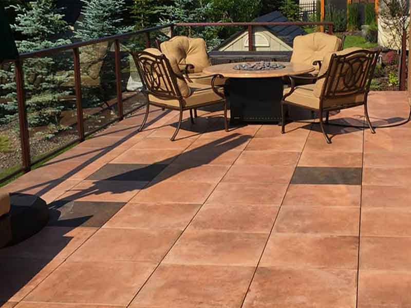 Teracotta colored porcelain paver patio with table, chairs, and glass balcony fence.
