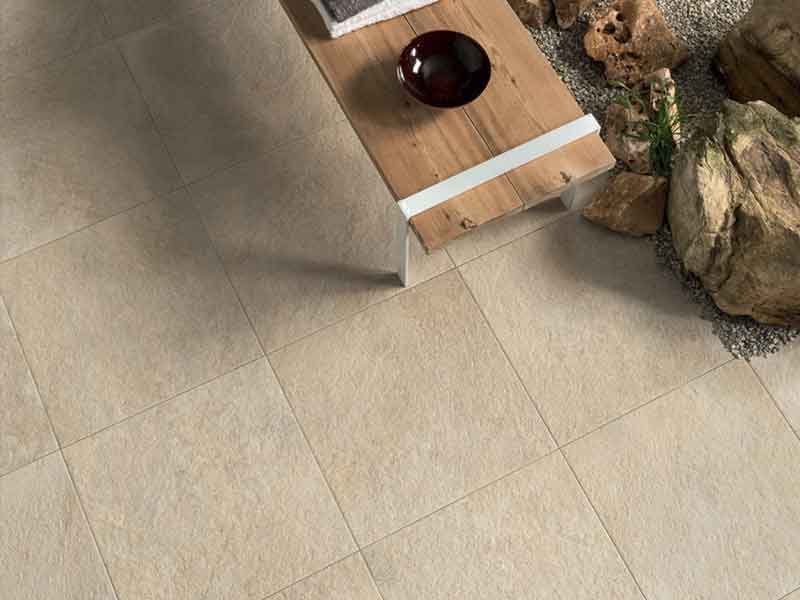cream colored porcelain pavers on-grade with small bench.
