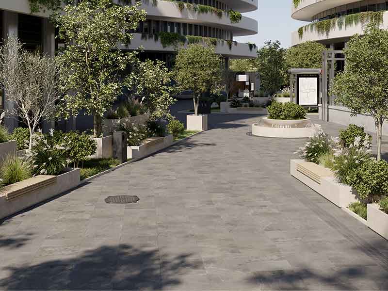 greyish blue porcelain pavers in a plaza with lush landscaping and trees around.