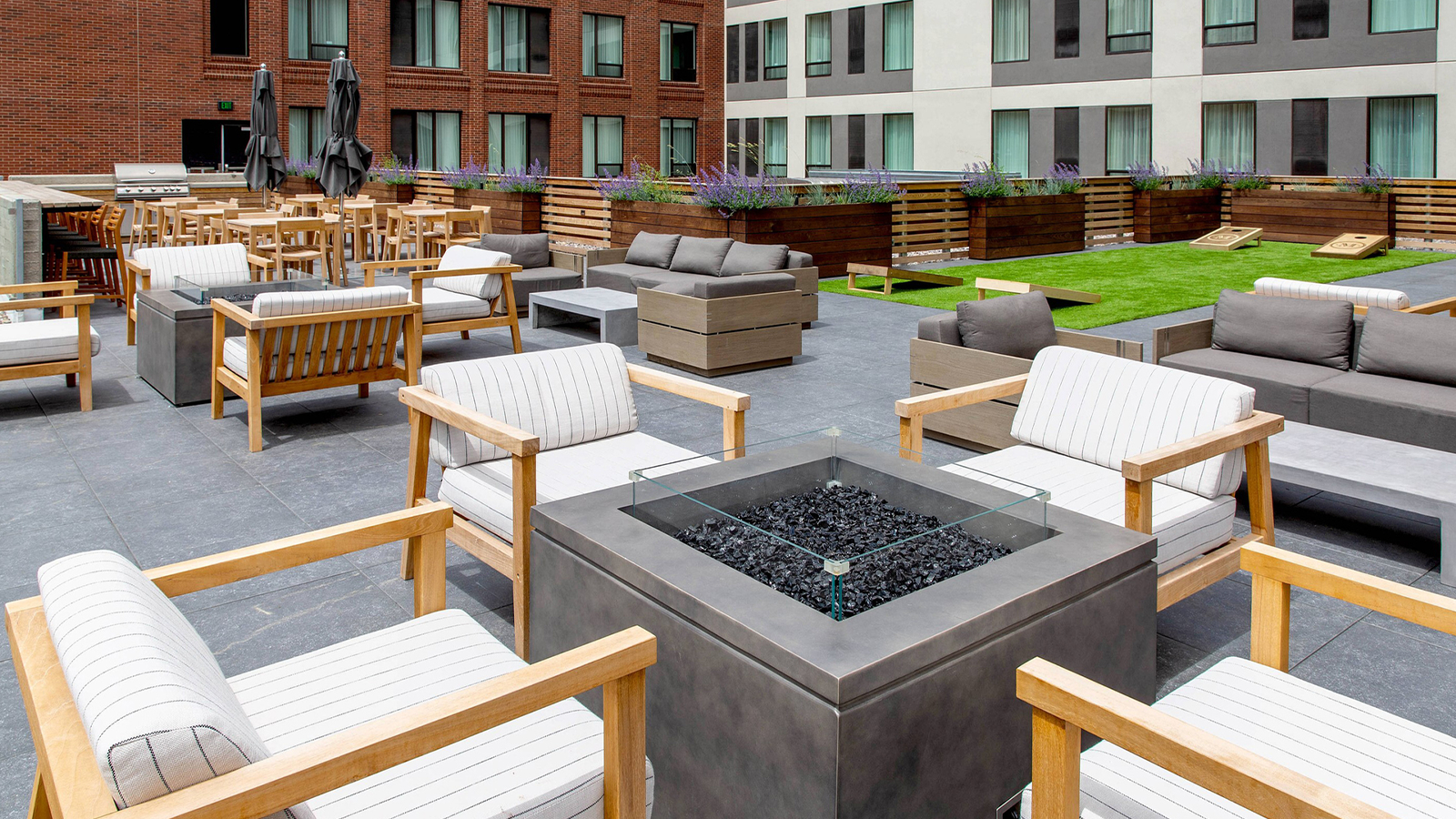 rooftop deck with raised firepit surrounded by white patio chairs. 