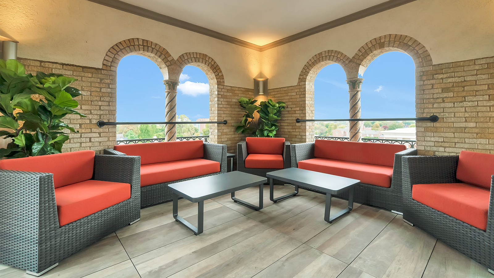 Rooftop lounge area with red couches and wood look porcelain paver flooring.