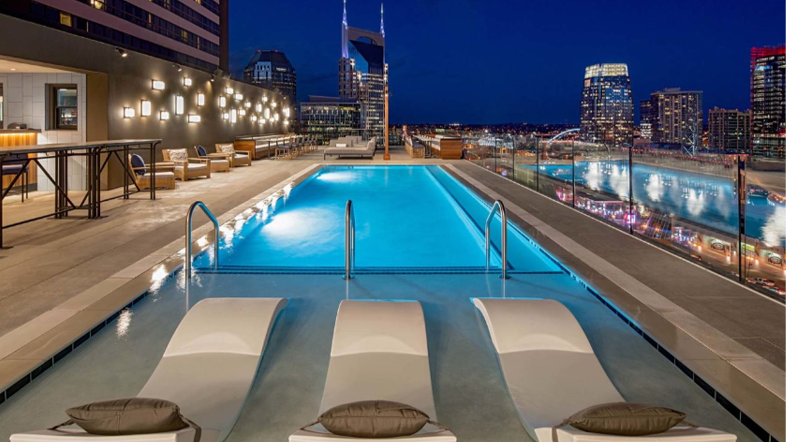 james robertson hotel pool at night with city views and lounge chairs in foreground