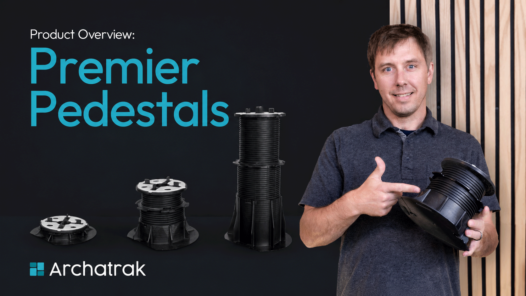 man holding a black decking pedestal and pointing at it.