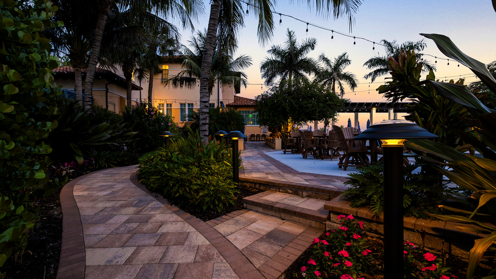 Solar bollards at dusk in a patio setting with palm trees around.