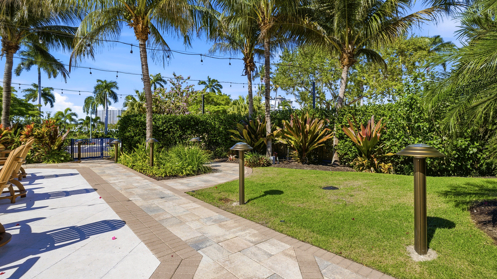 Solar bollards next to a path with palm trees in the background. 