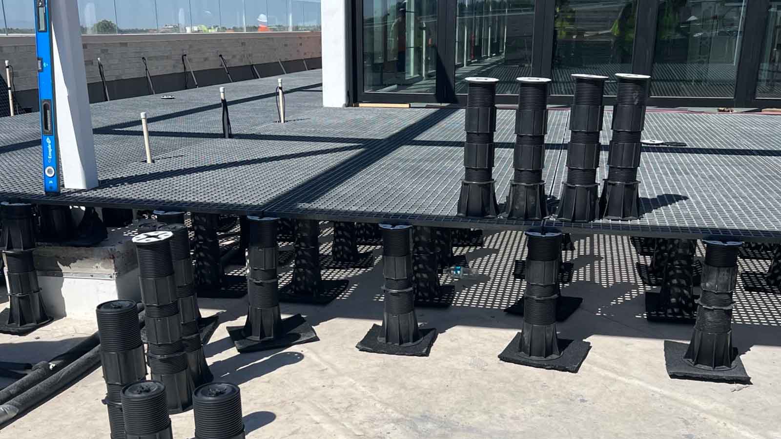 FRP grating resting on top of black adjustable height pedestals on a roof deck.