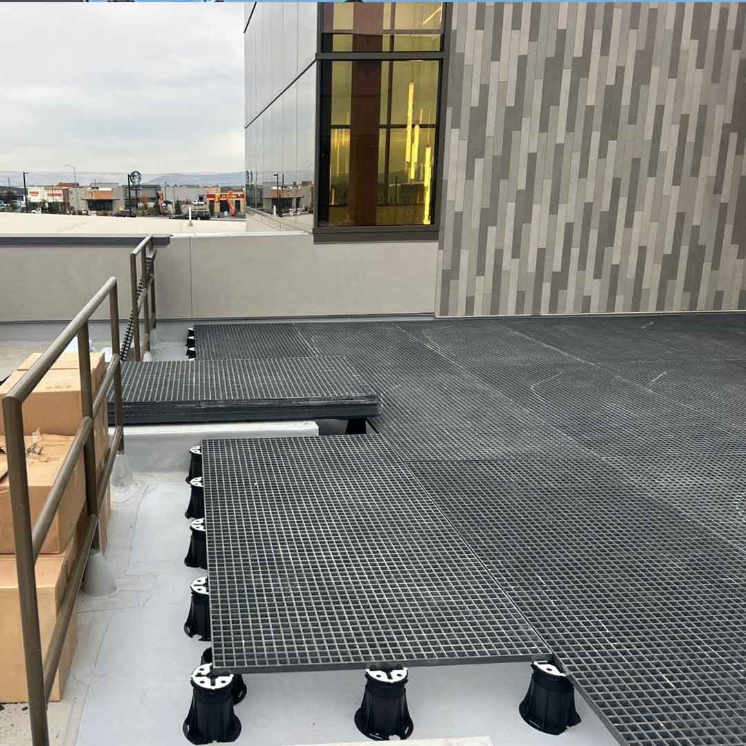 FRP grating panels over black adjustable pedestals on a roof deck. 
