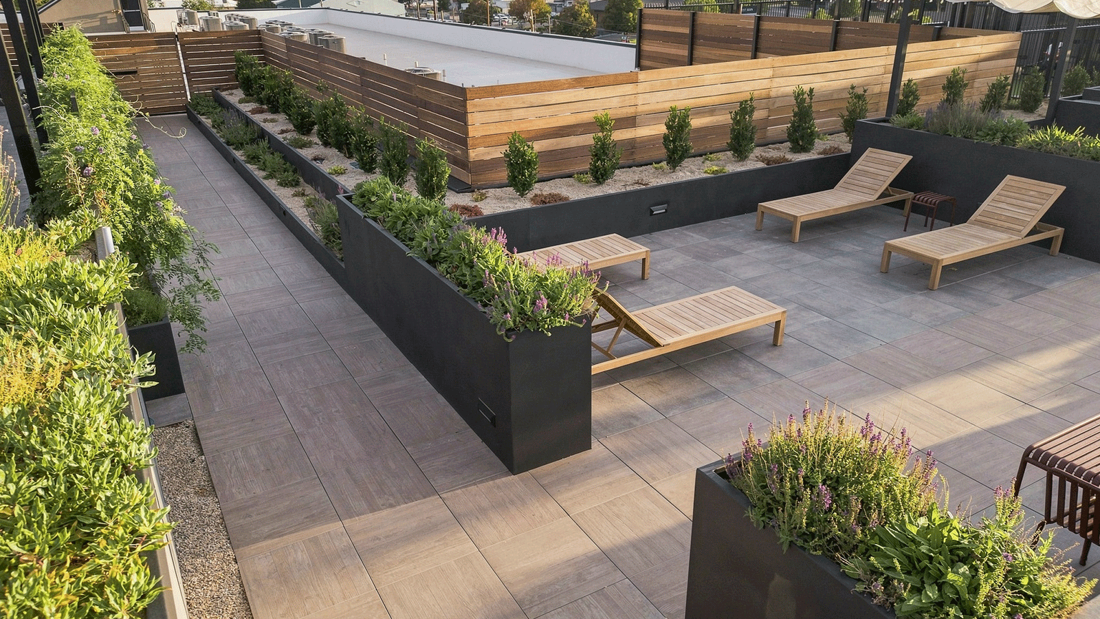rooftop deck with porcleain paver surface and greenery in dark grey planters.