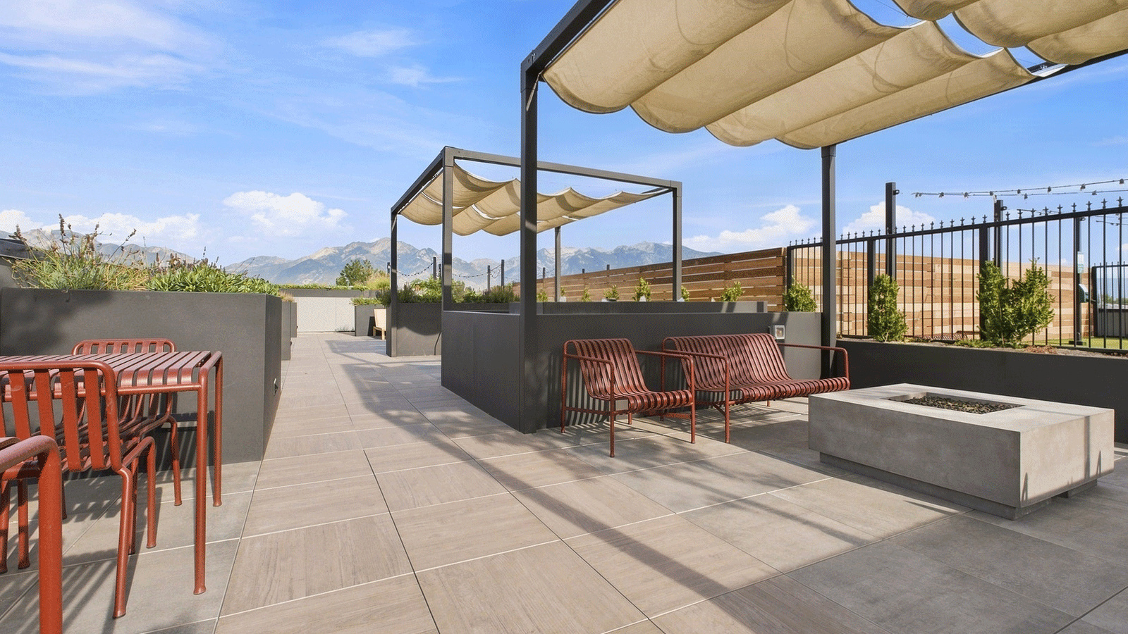 roof top deck with wood look procelan pavers, red chairs on the right and fire pit on the left.