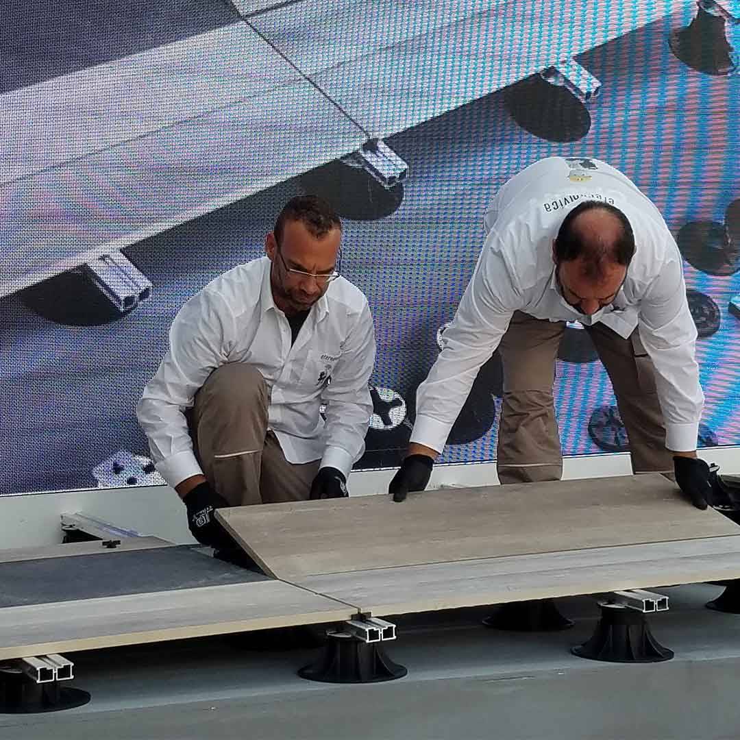 two men adding porcelain planks over rail and pedestal flooring system